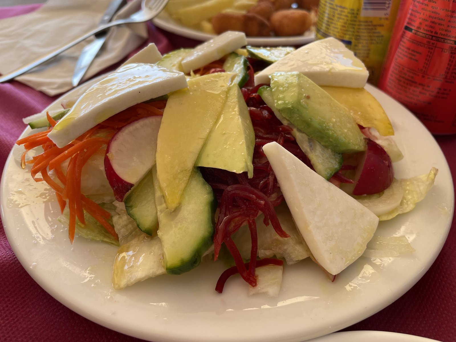 Een salade met avocado, stukken kaas en gesneden groenten.